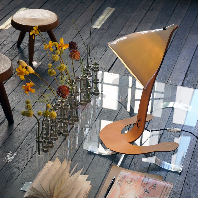 Grande lampe en porcelaine avec pied en bois, sur une table vitrée