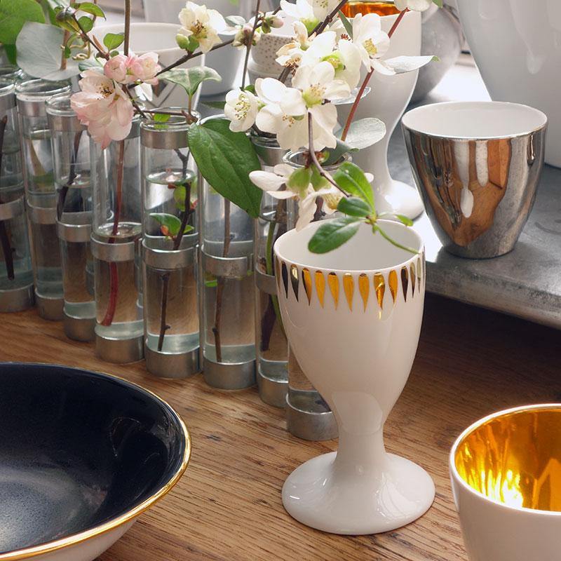 verre à pied blanc et or à côté d'un vase d'avril tsé tsé - tsé tsé