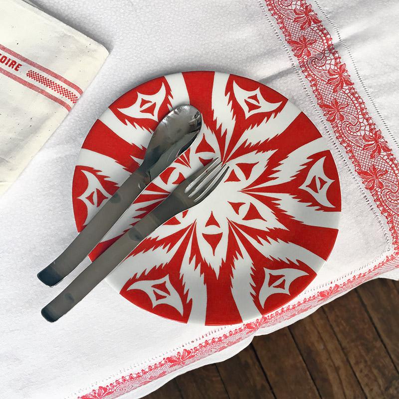 assiette rouge inspiration ikat, avec couverts posés dessus. Modèle "Chirchik" - tsé tsé