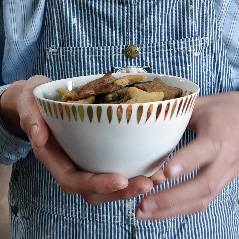 biscuits dans un bol blanc et or de forme irrégulière tenu en main - tsé tsé