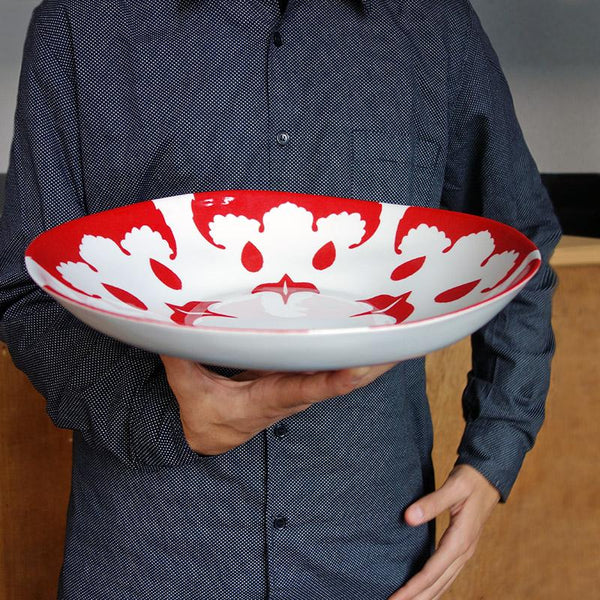 gros plan sur un grand plat creux rouge et blanc en porcelaine tenu en main - tsé tsé