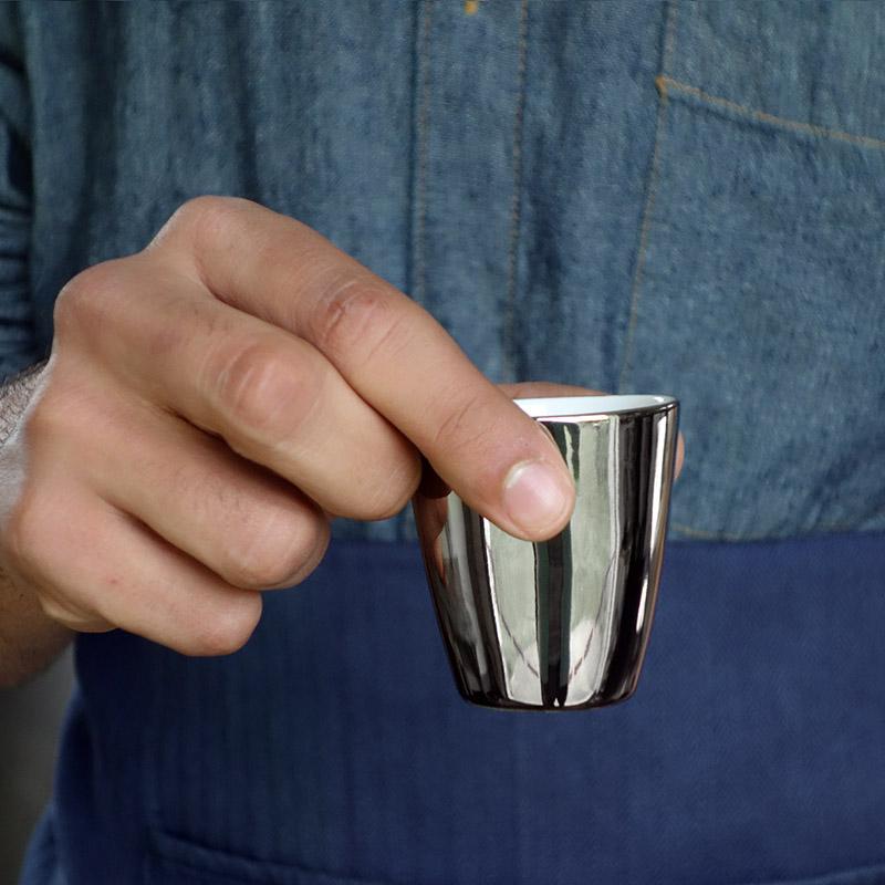 gros plan sur gobelet à expresso argenté tenu à deux doigts - tsé tsé