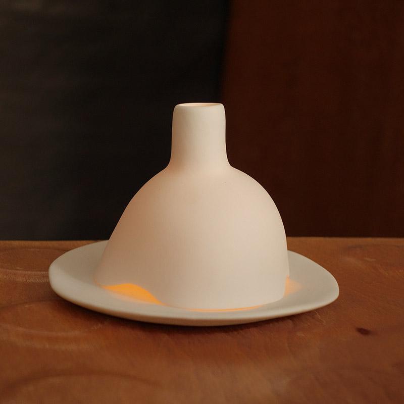 bougie allumée dans un photophore blanc en porcelaine mate - tsé tsé