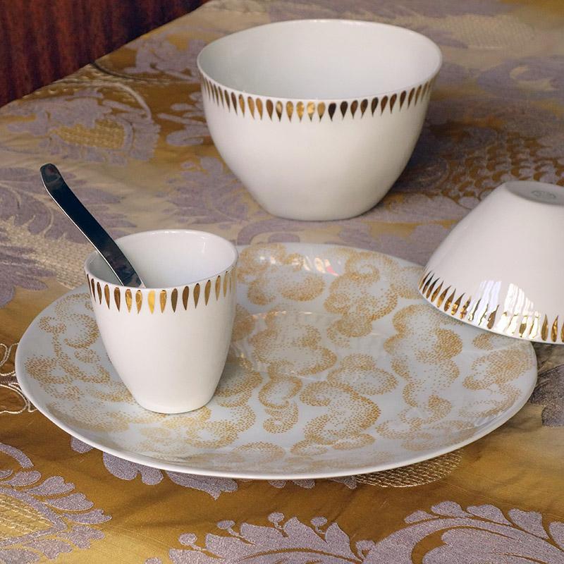 vaisselle en porcelaine blanche et or sur une nappe dorée - tsé tsé