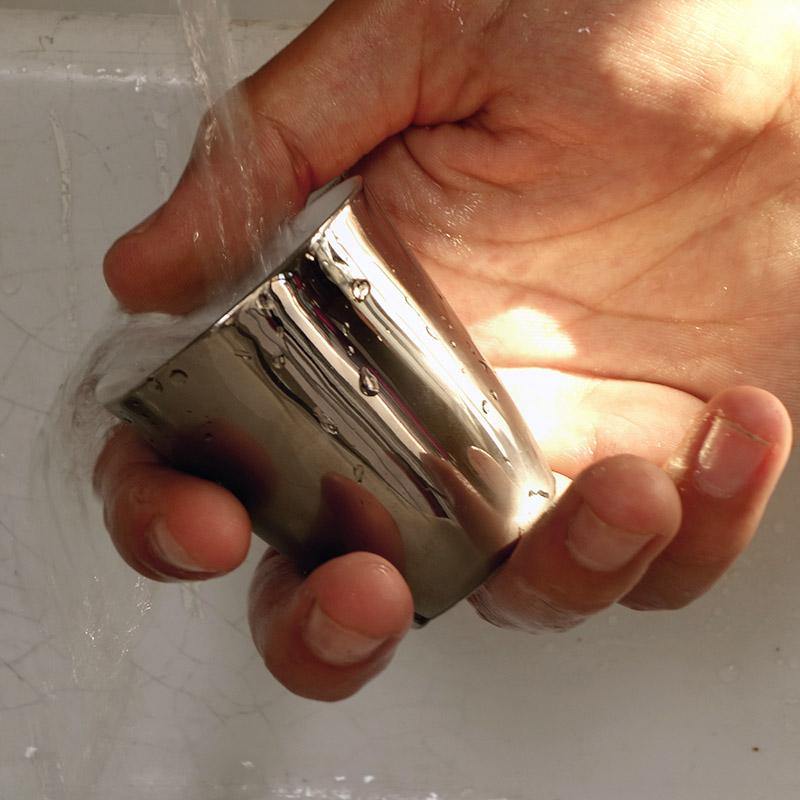 petite tasse à expresso argentée en train d'être passée sous l'eau - tsé tsé