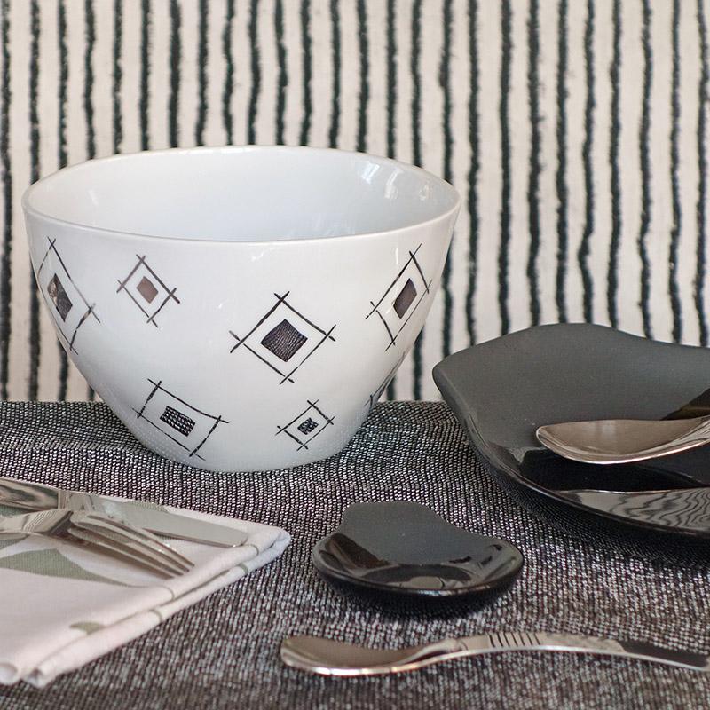 assiettes noires et saladier blanc à motifs argentés effet miroir devant un mur noir et blanc rayé - tsé tsé