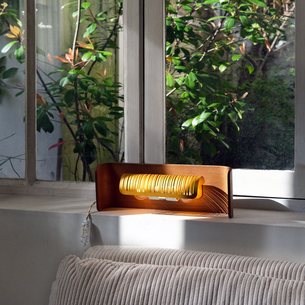Lampe en bois et laiton devant une fenêtre. Design Tsé & Tsé