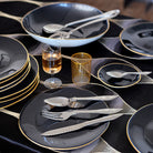 table de fête avec assiettes et plats noirs et bordure or