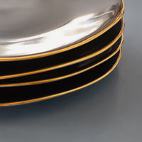 détail d'une pile d'assiettes noires avec rebords or