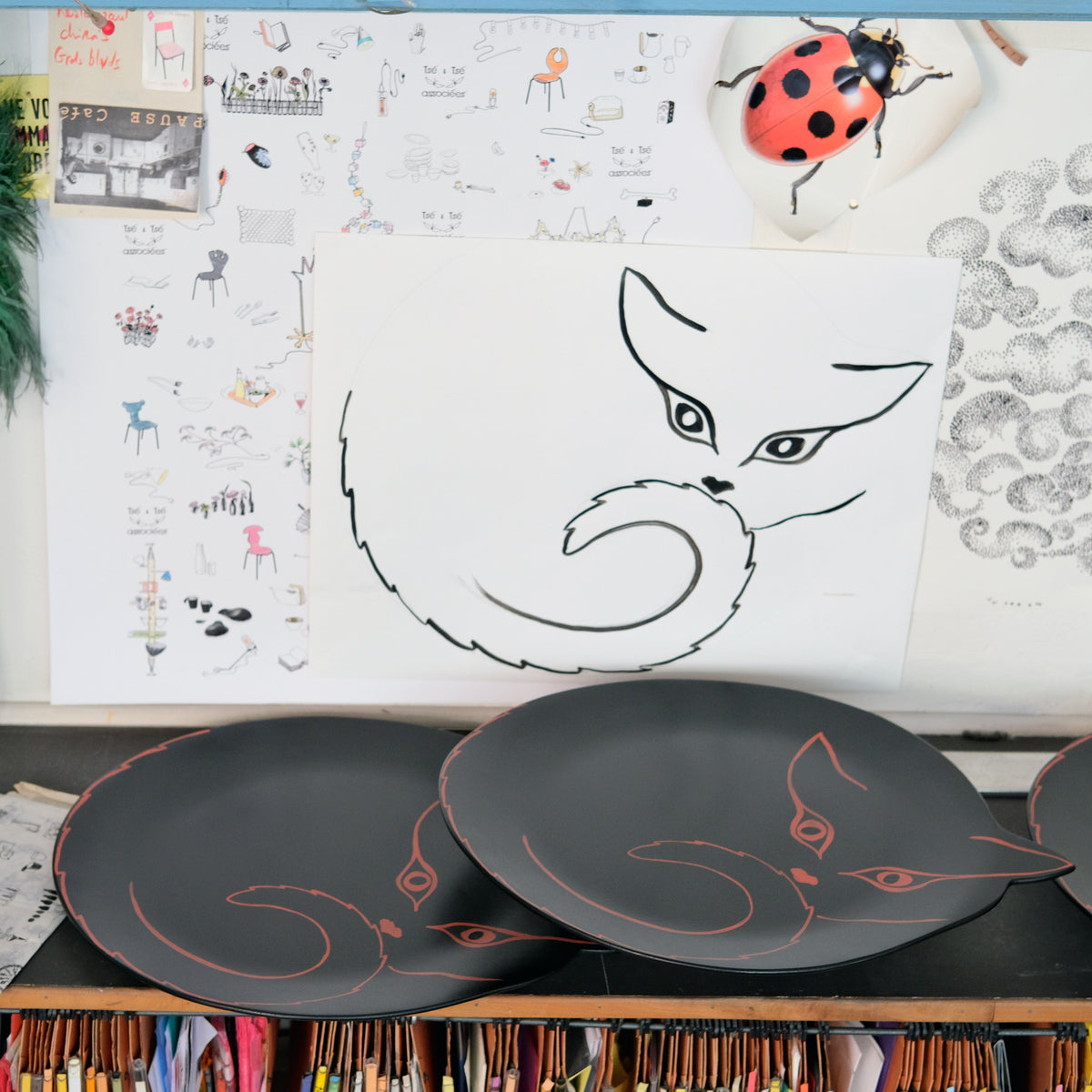 dessin léger d'une silhouette de chat, sur papier et sur plateaux en bois