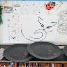 dessin léger d'une silhouette de chat, sur papier et sur plateaux en bois