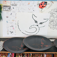 dessin léger d'une silhouette de chat, sur papier et sur plateaux en bois