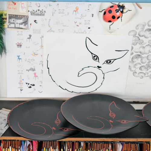 dessin léger d'une silhouette de chat, sur papier et sur plateaux en bois