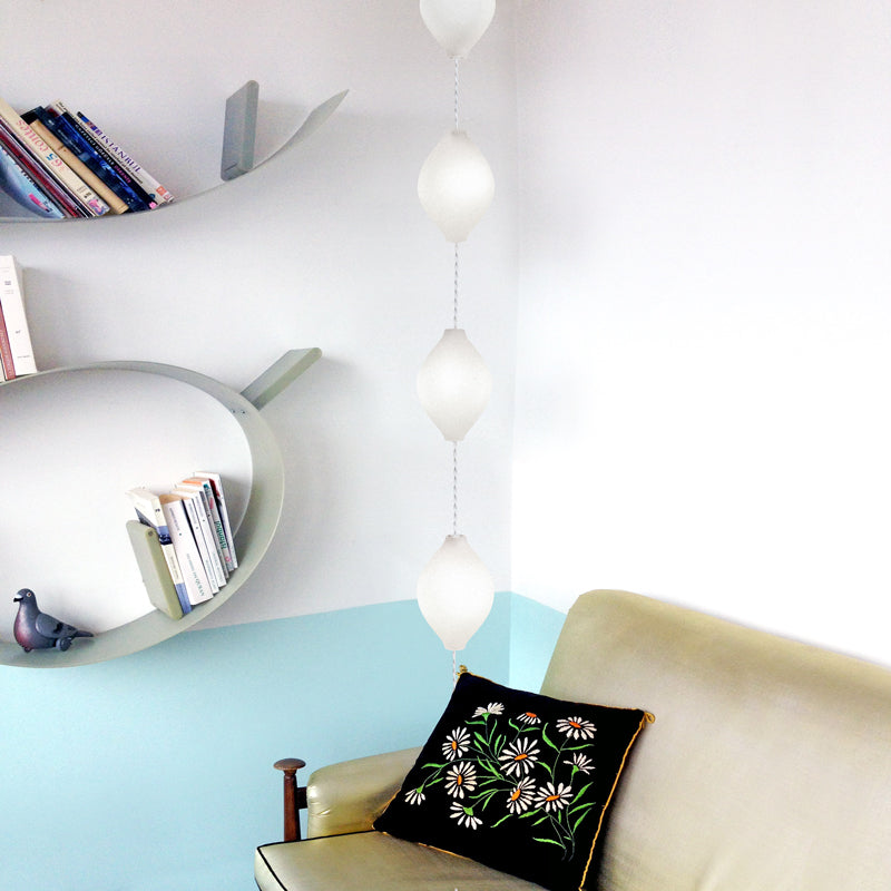 Lampe en verre suspendue à la verticale dans un coin salon