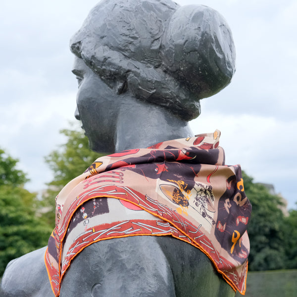 Foulard en soie Tsé & Tsé 90x90 cm noué autour du cou d’une statue, avec motifs du Vase d’Avril, théière Mirza, lampe Cornette, Vaisselle Affamée, chaise Enthousiaste, clé à molette, vase Oiseau, Petite Théière, lampe squelettique, vase Paresseux, lampe Pilaf, Igloo de Nuit