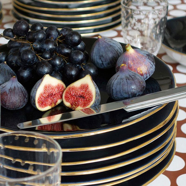 fruits et couteau de forme originale posés sur une pile d'assiettes en porcelaine bleu sombre avec un liseré doré - tsé tsé