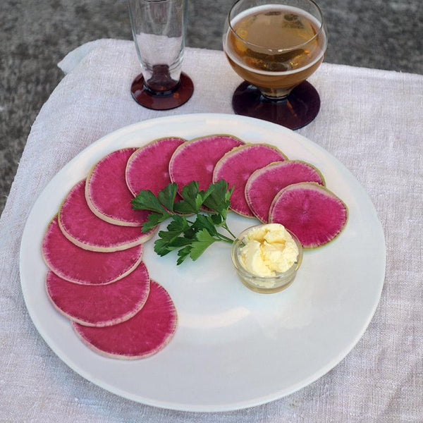 tranches de gros radis roses et beurre dans une grande assiette blanche de forme irrégulière - tsé tsé