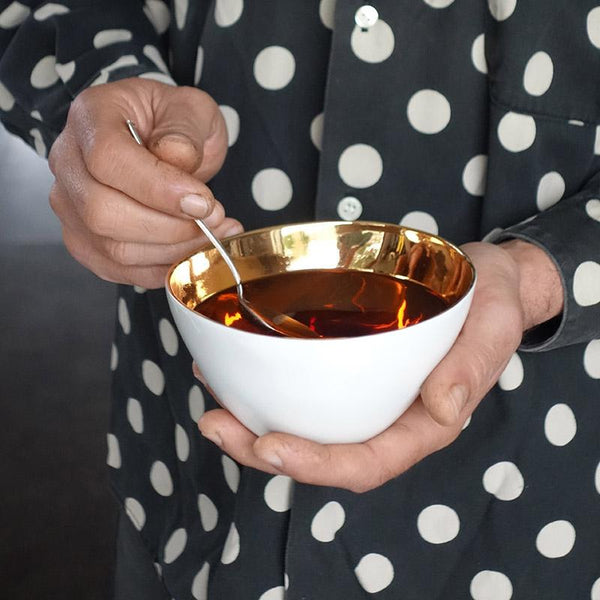 bol de thé en porcelaine blanche avec l'intérieur en or tenu en main - tsé tsé