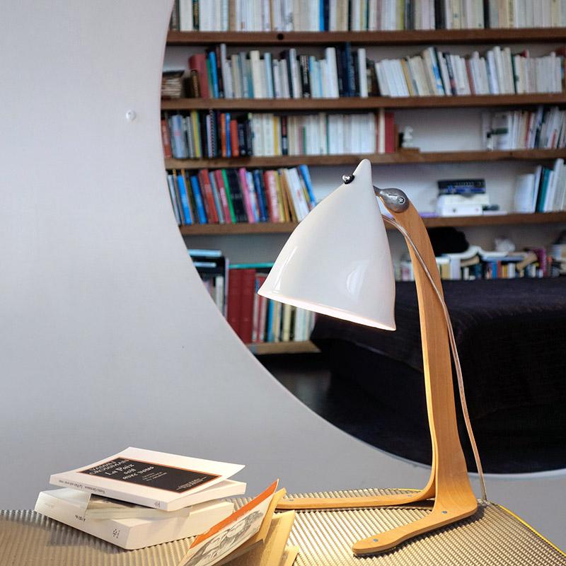 lampe de bureau en porcelaine émaillée et pied en bois devant une bibliothèque - tsé tsé