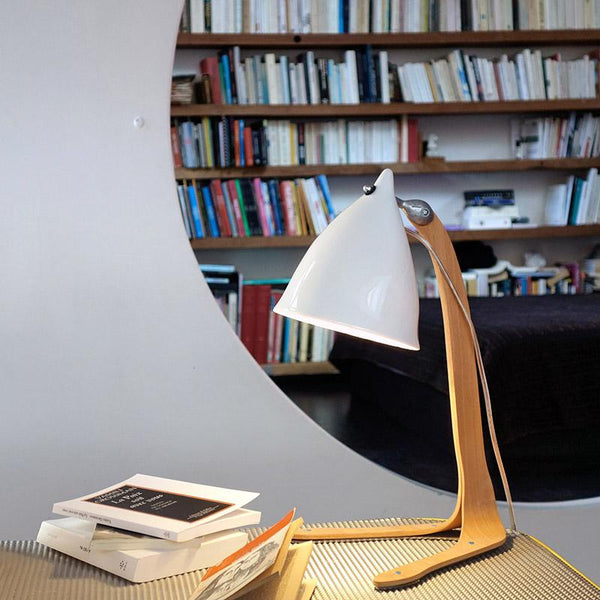 lampe de bureau en porcelaine émaillée et pied en bois devant une bibliothèque - tsé tsé