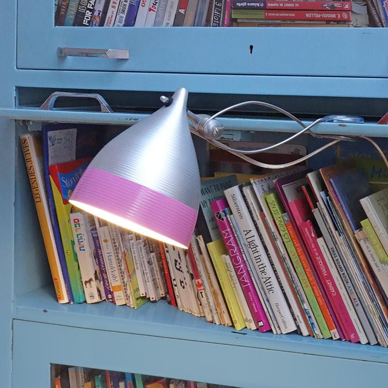 lampe à pince en alu bicolore gris et rose sur une bibliothèque bleue - tsé tsé