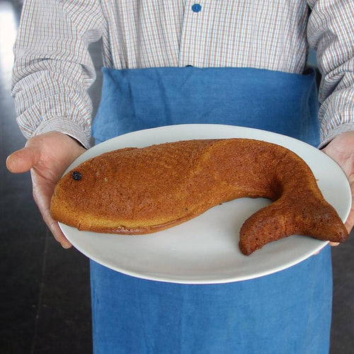 grande assiette à gâteau blanche tenue en main avec un gâteau poisson dedans - tsé tsé