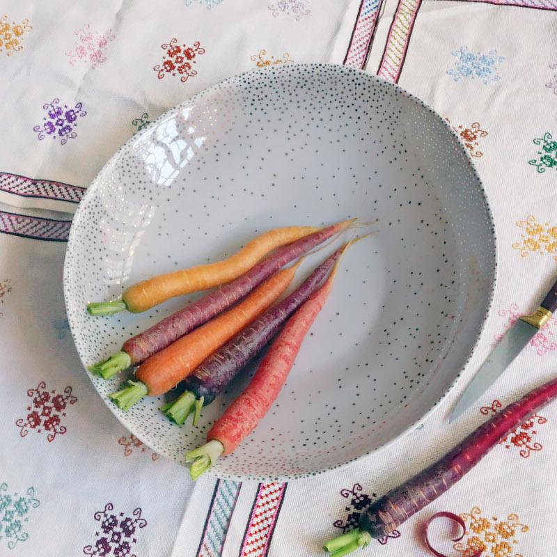 carottes multicolores dans un grand plat en porcelaine blanche avec des pois argentés - tsé tsé