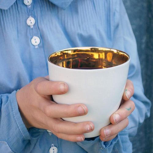 grande tasse sans poignée en porcelaine blanche et intérieur or tenue en main - tsé tsé