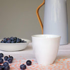tasse à thé en porcelaine de forme irrégulière avec des myrtilles en arrière-plan - tsé tsé