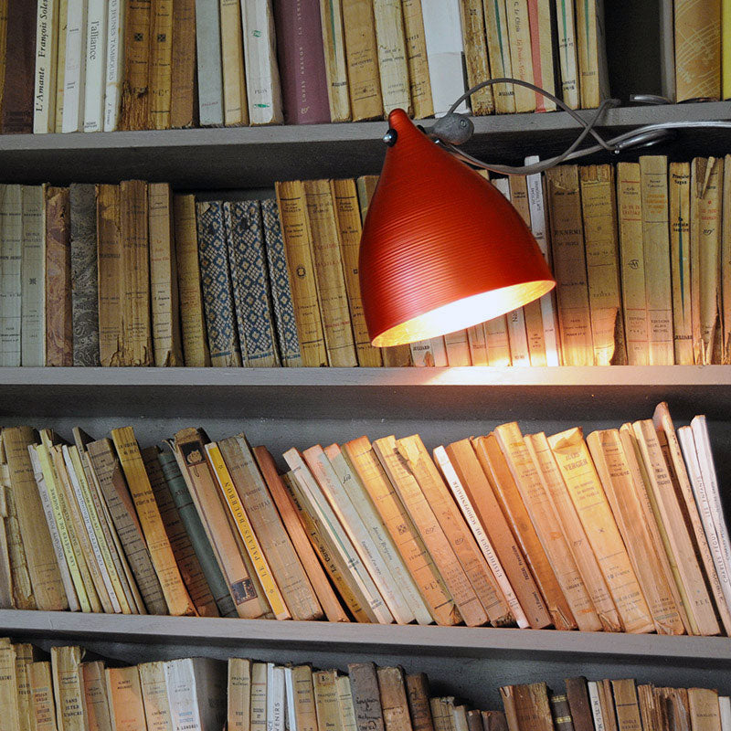 lampe à pince rouge en aluminium anodisé accrochée à une bibliothèque - tsé tsé