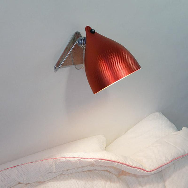 luminaire rouge métallisé fixé au mur au dessus d'un lit - tsé tsé