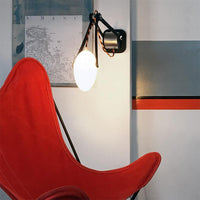 applique articulée en bois noir éclairant un fauteuil papillon rouge - tsé tsé