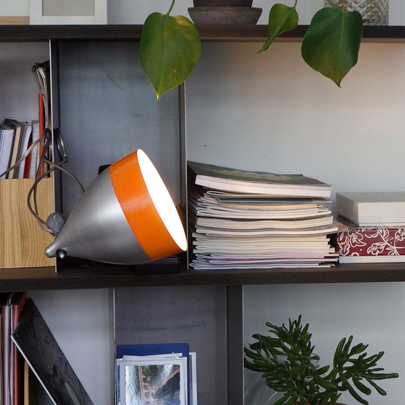 lampe orange et grise en aluminium laqué avec fixée par une pince à une étagère - tsé tsé