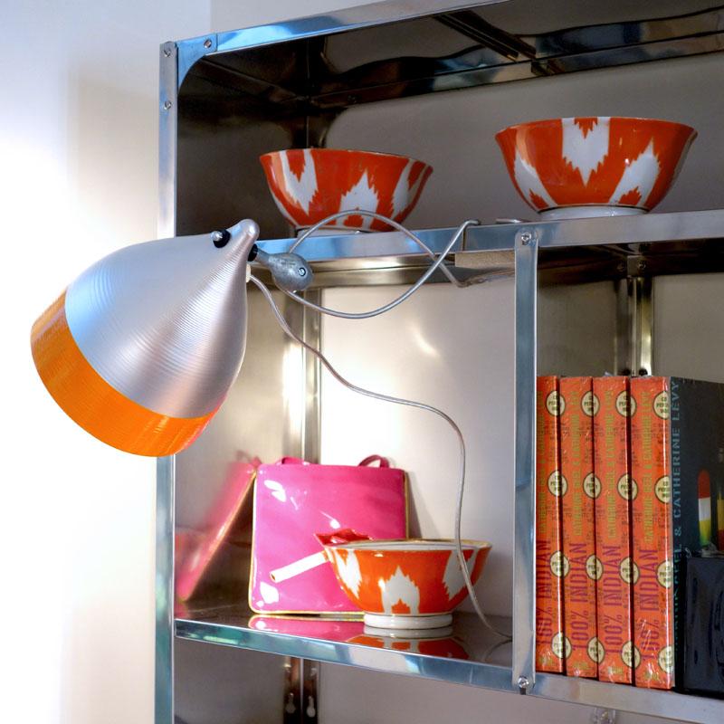 lampe à pince bicolore orange et gris sur une étagère en inox - tsé tsé