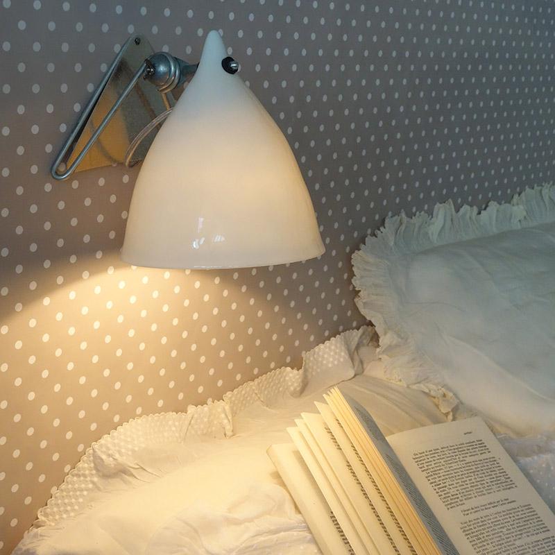 lampe murale éclairant une tête de lit et un livre posé sur un oreiller - tsé tsé