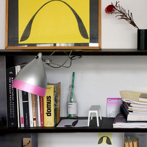 lampe grise et rose fixée par une pince à une étagère noire - tsé tsé
