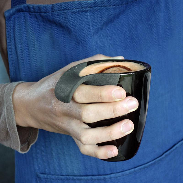gros plan sur une main qui tient une tasse noire remplie de café - tsé tsé