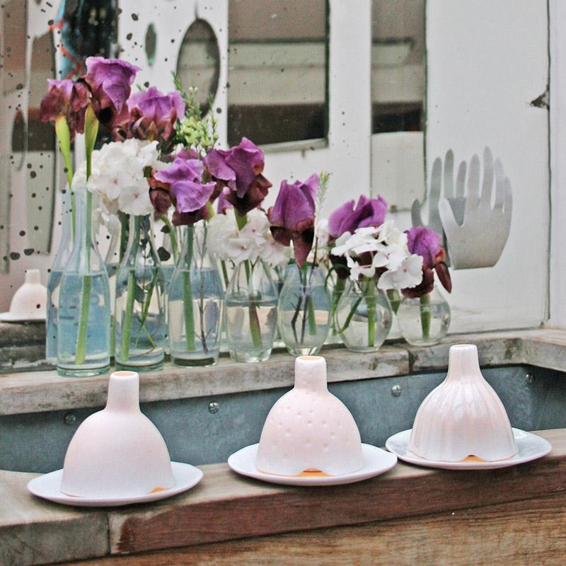 trois photophores igloo en porcelaine blanche devant des iris dans des vases individuels - tsé tsé