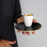 tasse à expresso posée sur une sous-tasse en porcelaine noire et or - tsé tsé