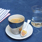 tasse à café argentée sur soucoupe en porcelaine blanche - tsé tsé
