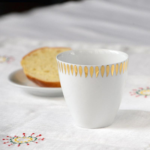 tasse blanche avec motifs en or sur nappe brodée - tsé tsé