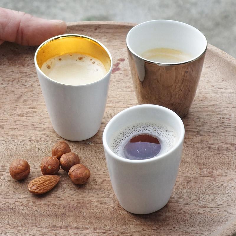 trio de petites tasses à café assorties en porcelaine blanche, or et argent sur un plateau rond en bois - tsé tsé