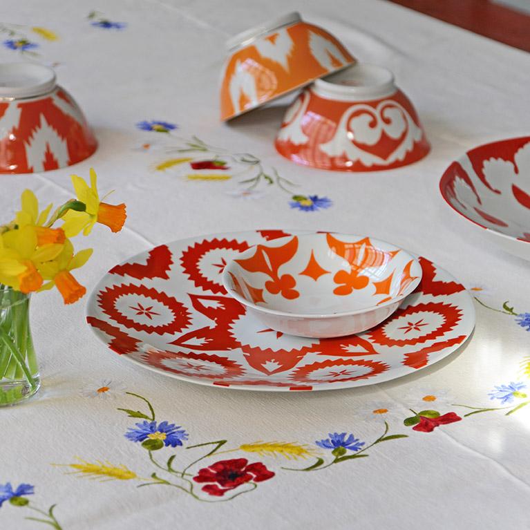vaisselle à motifs colorés orange et rouge d'inspiration ouzbek posés sur une nappe fleurie - tsé tsé